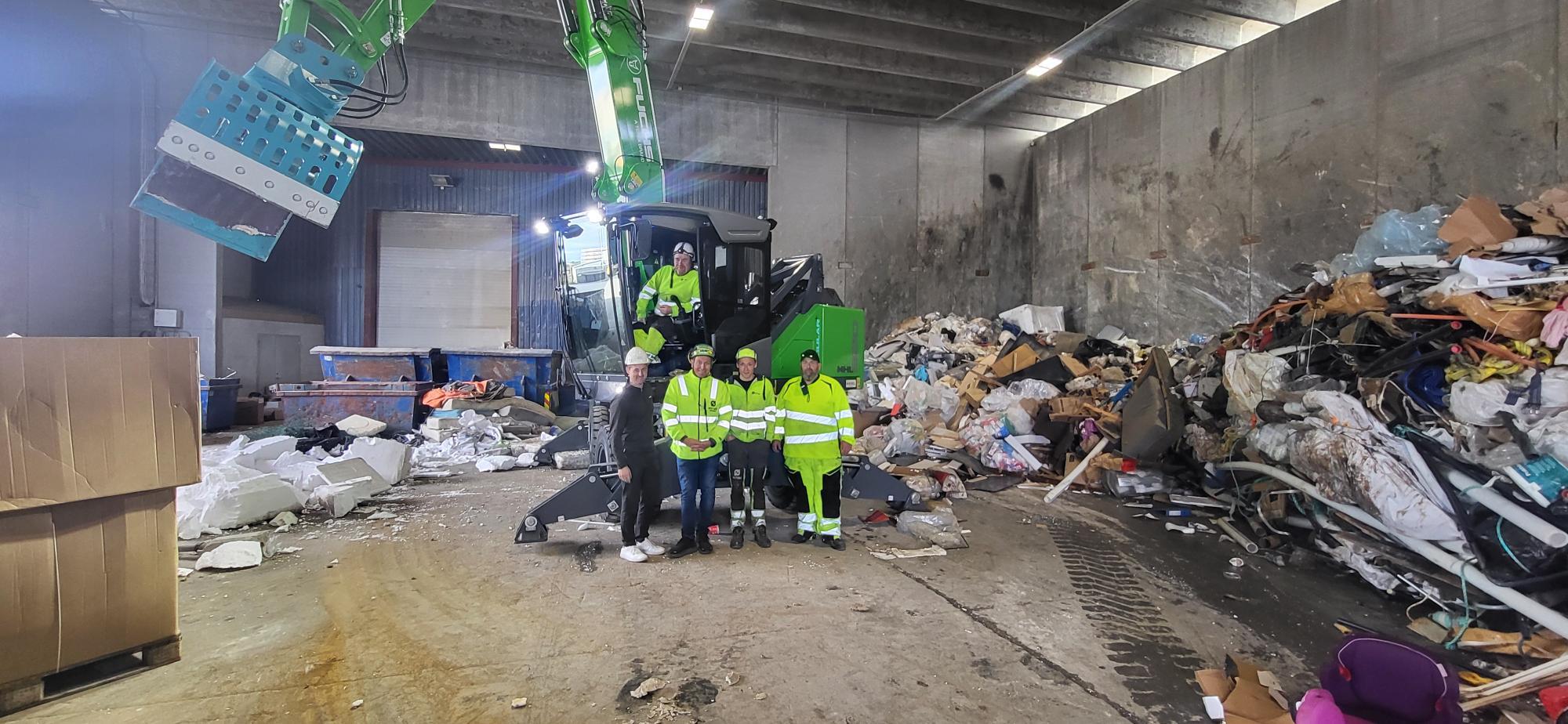 Den grønne maskinen i avfallshallen til Østbø, med ansatte i maskinen og foran. 
